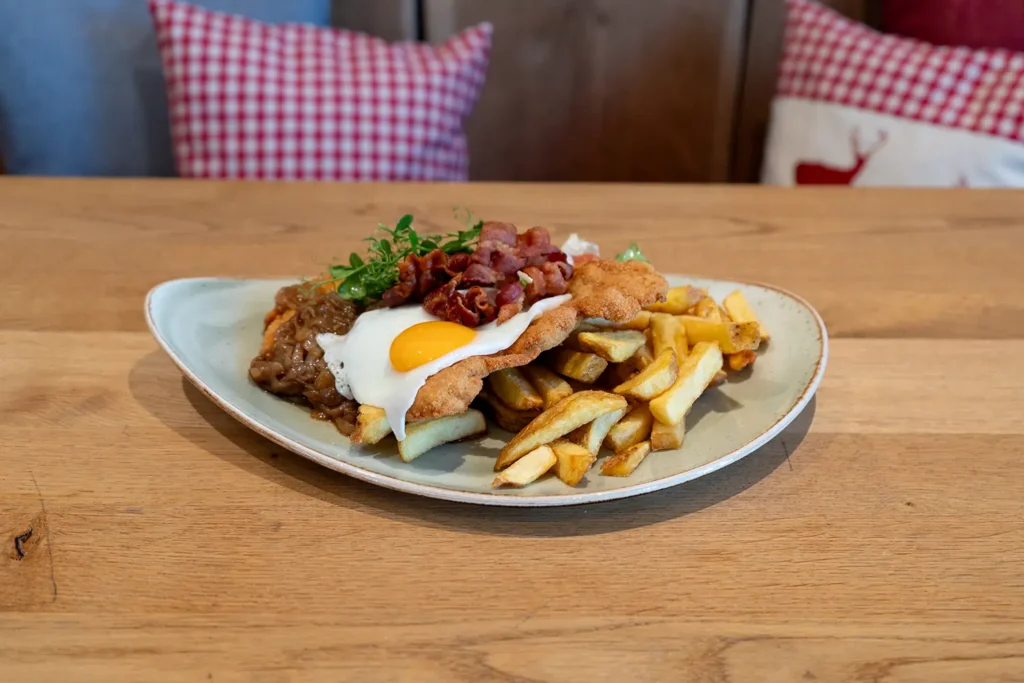Ein Schnitzel mit Zwiebeln, Spiegelei, Pommes und Speck