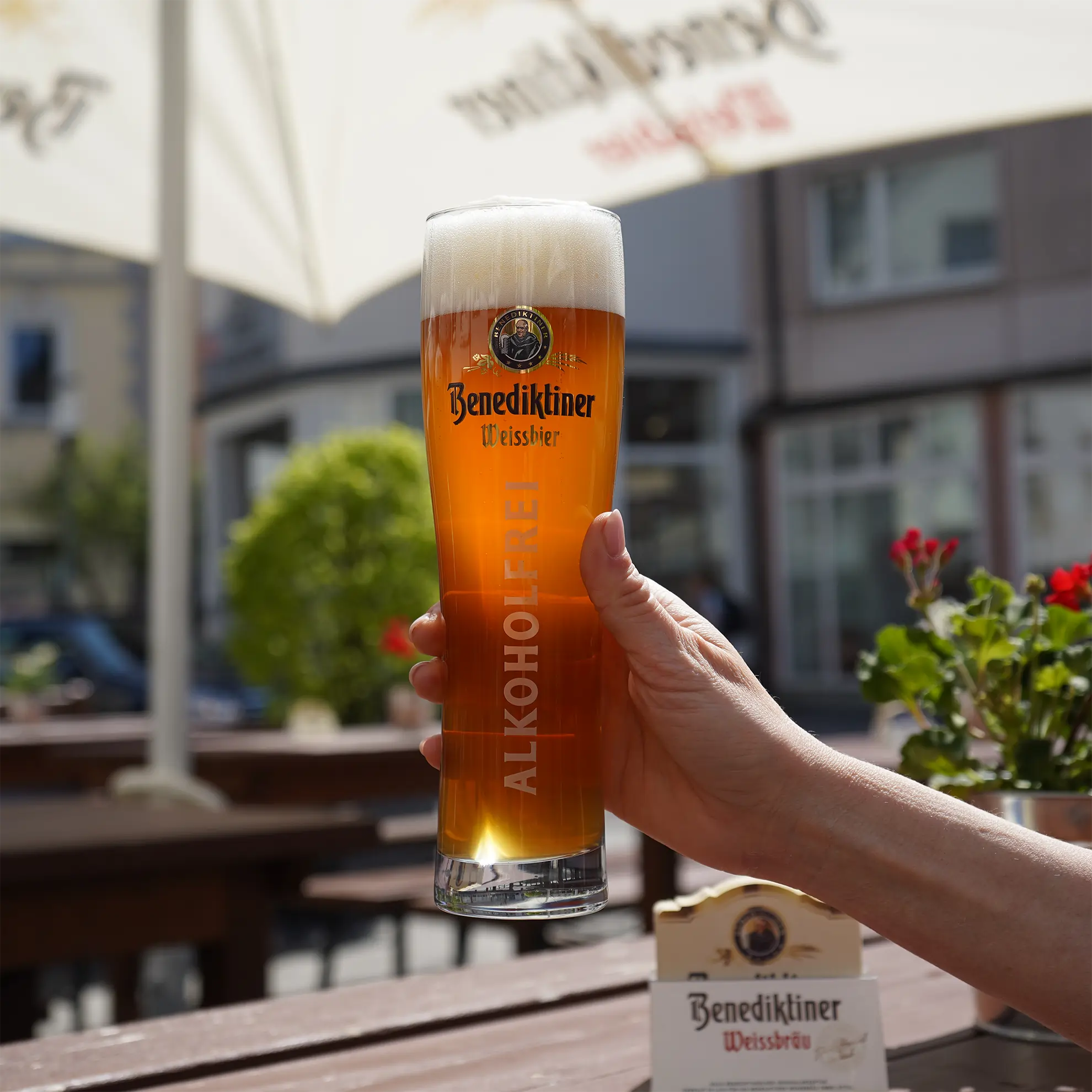 Ein Benediktiner Alkoholfrei wird im Biergarten in die Kamera gehalten