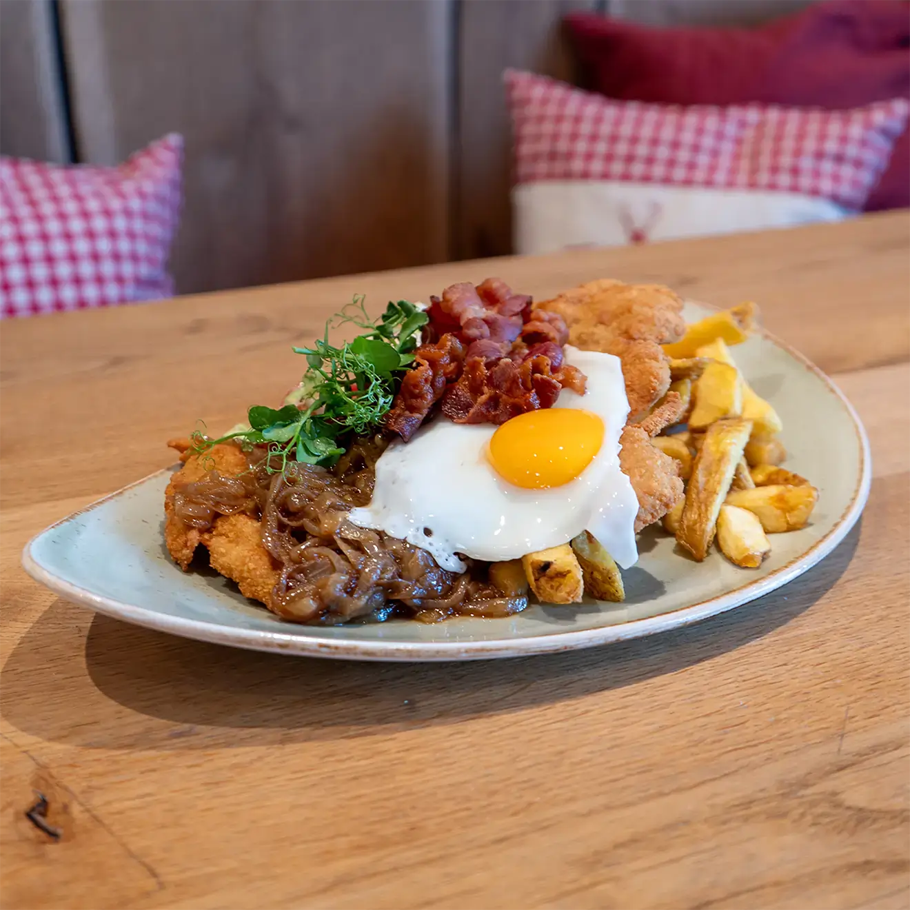 Ein Schnitzel mit Zwiebeln, Spiegelei, Pommes und Speck